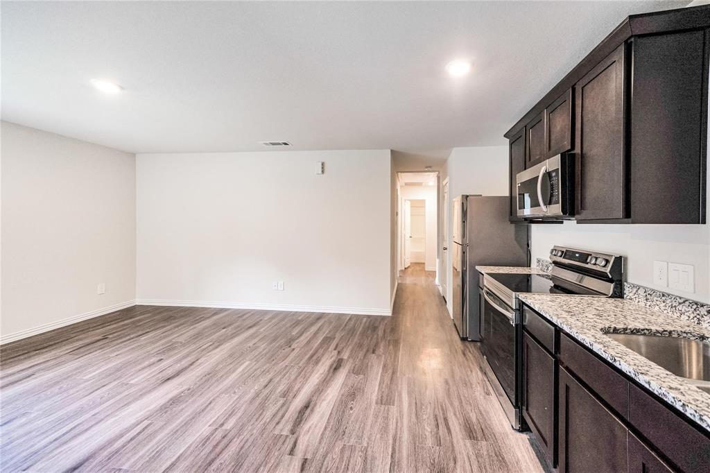 a kitchen with granite countertop a refrigerator stove top oven and sink