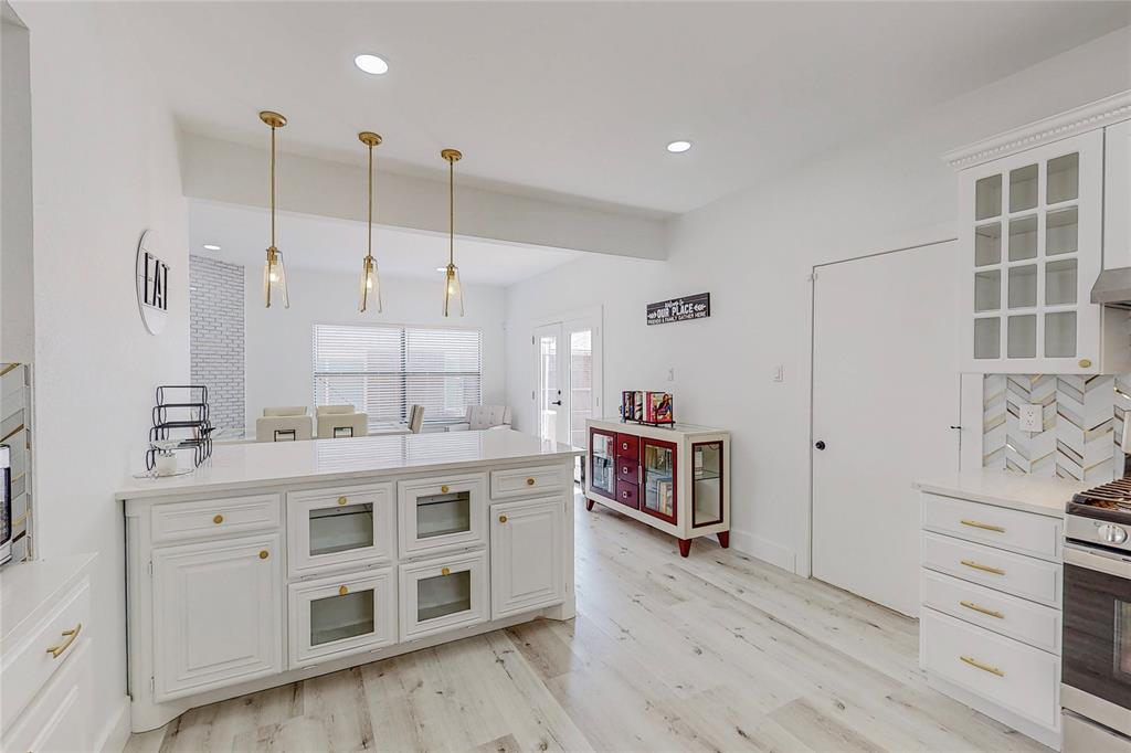 a large white kitchen with a stove a sink a window and wooden floor