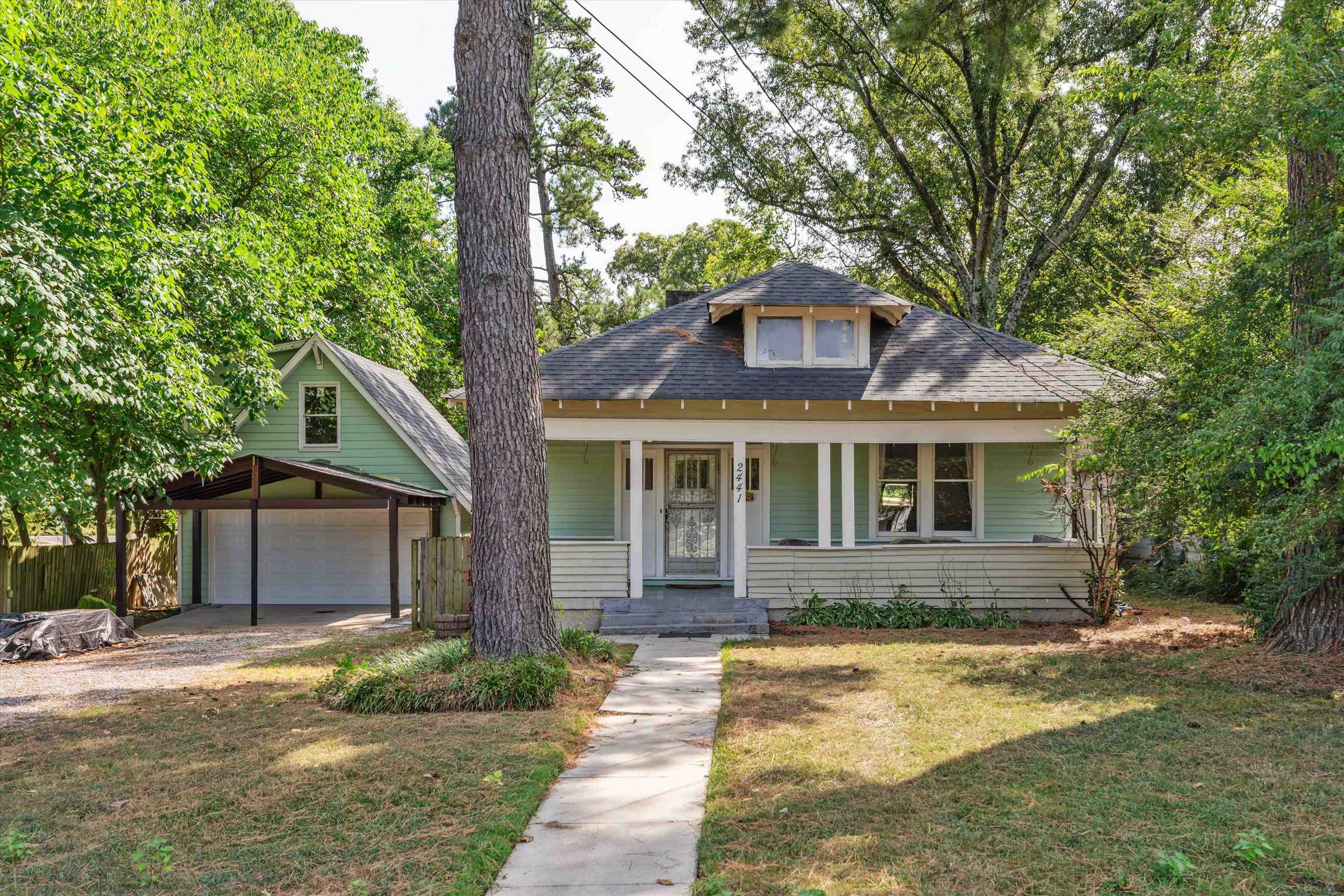 Bungalow featuring a garage, a front yard, and covered porch