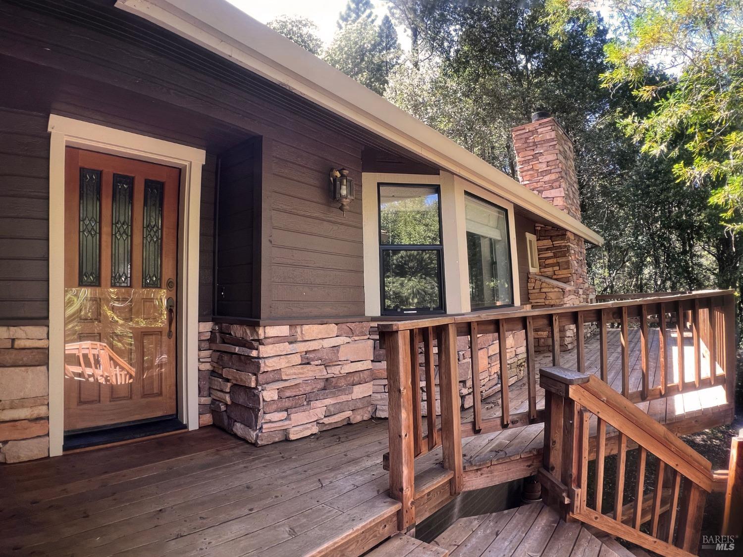 a view of deck with large trees and wooden fence