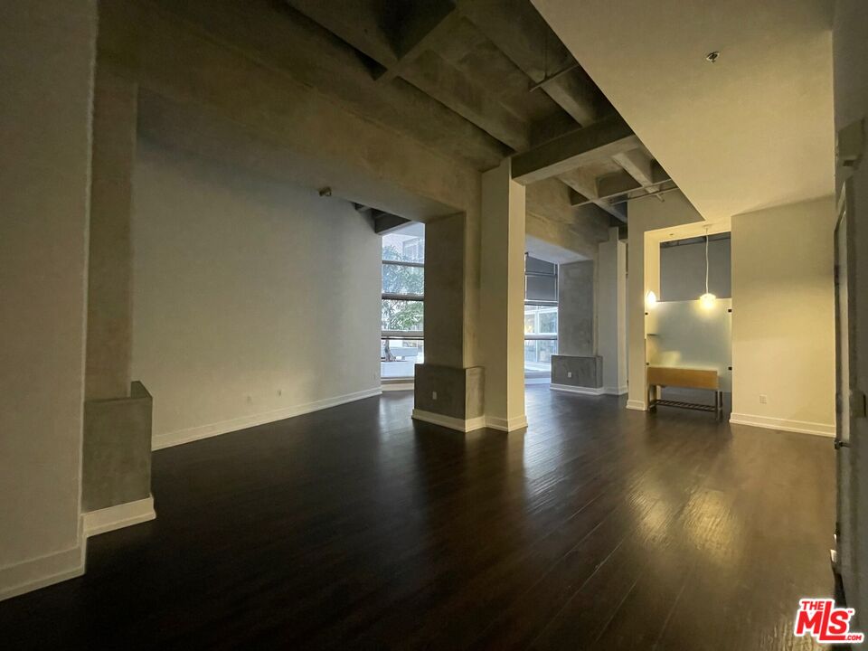 a view of an empty room with wooden floor and a bathroom