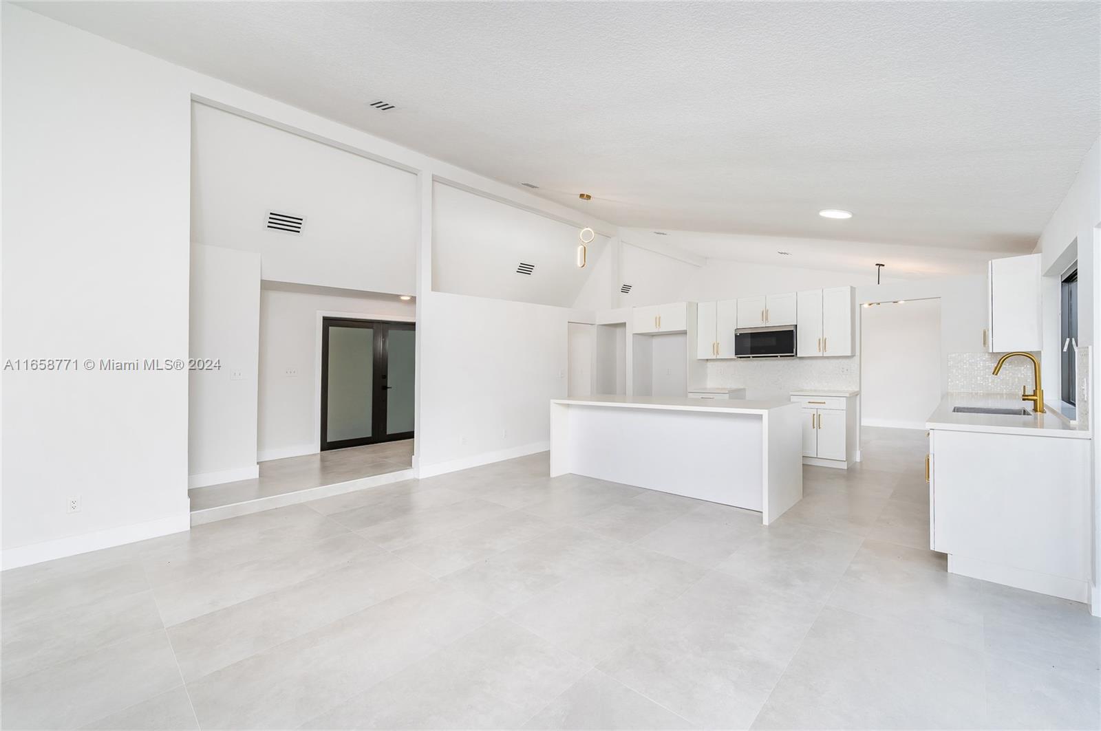 a large white kitchen with stainless steel appliances kitchen island a white counter space a sink and a stove