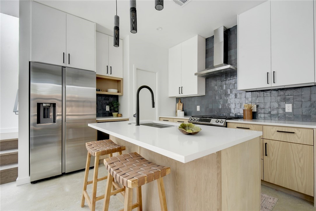 a kitchen with stainless steel appliances a refrigerator a sink a stove and white cabinets