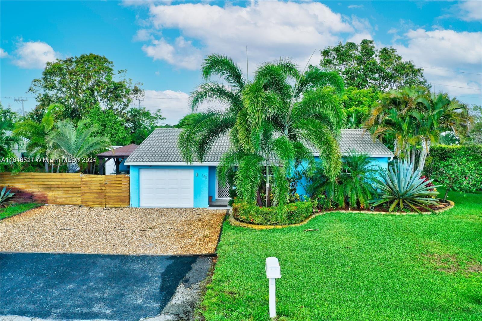 a view of a house with a yard and a large tree