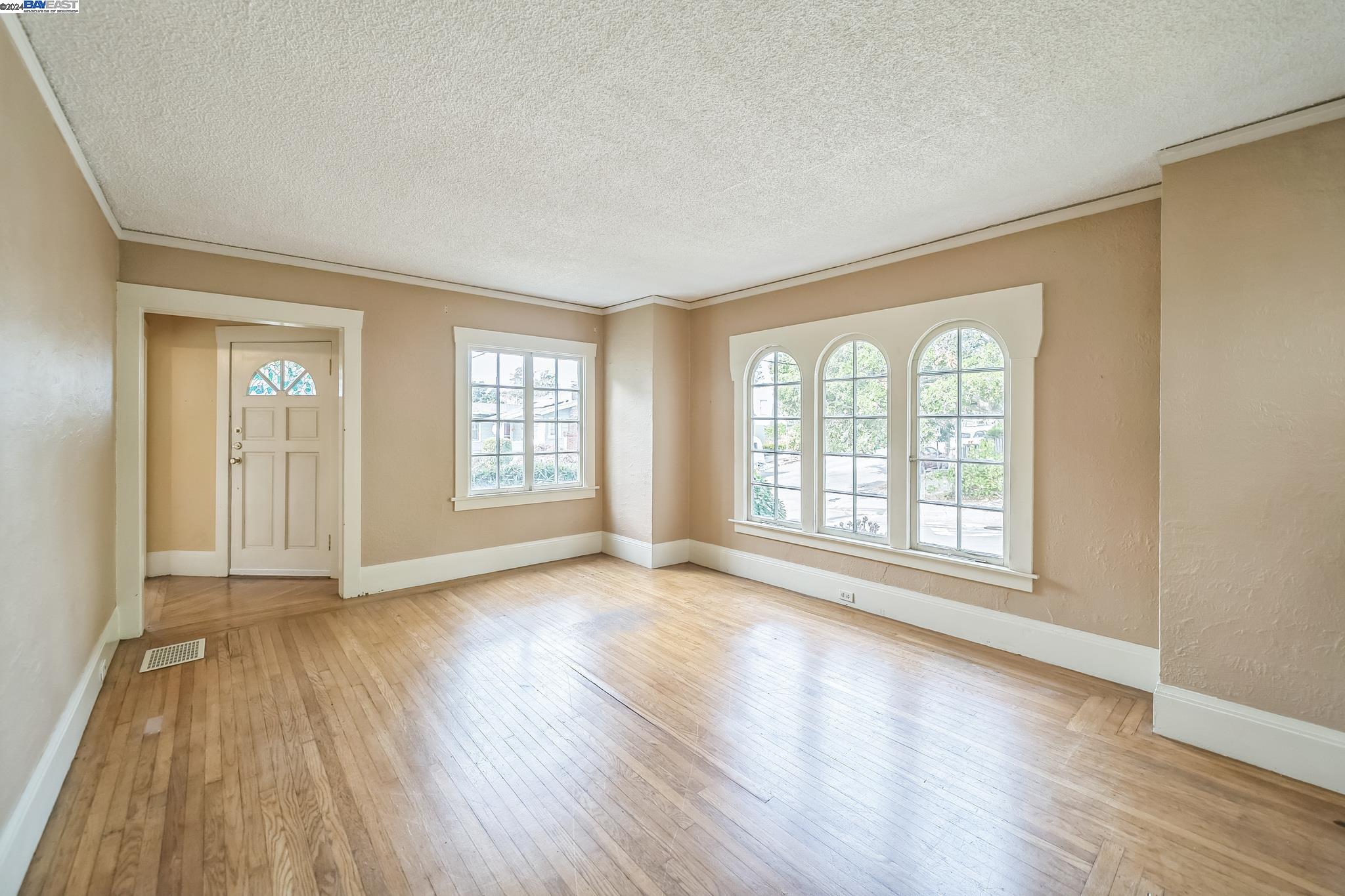 a view of an empty room with wooden floor and a window