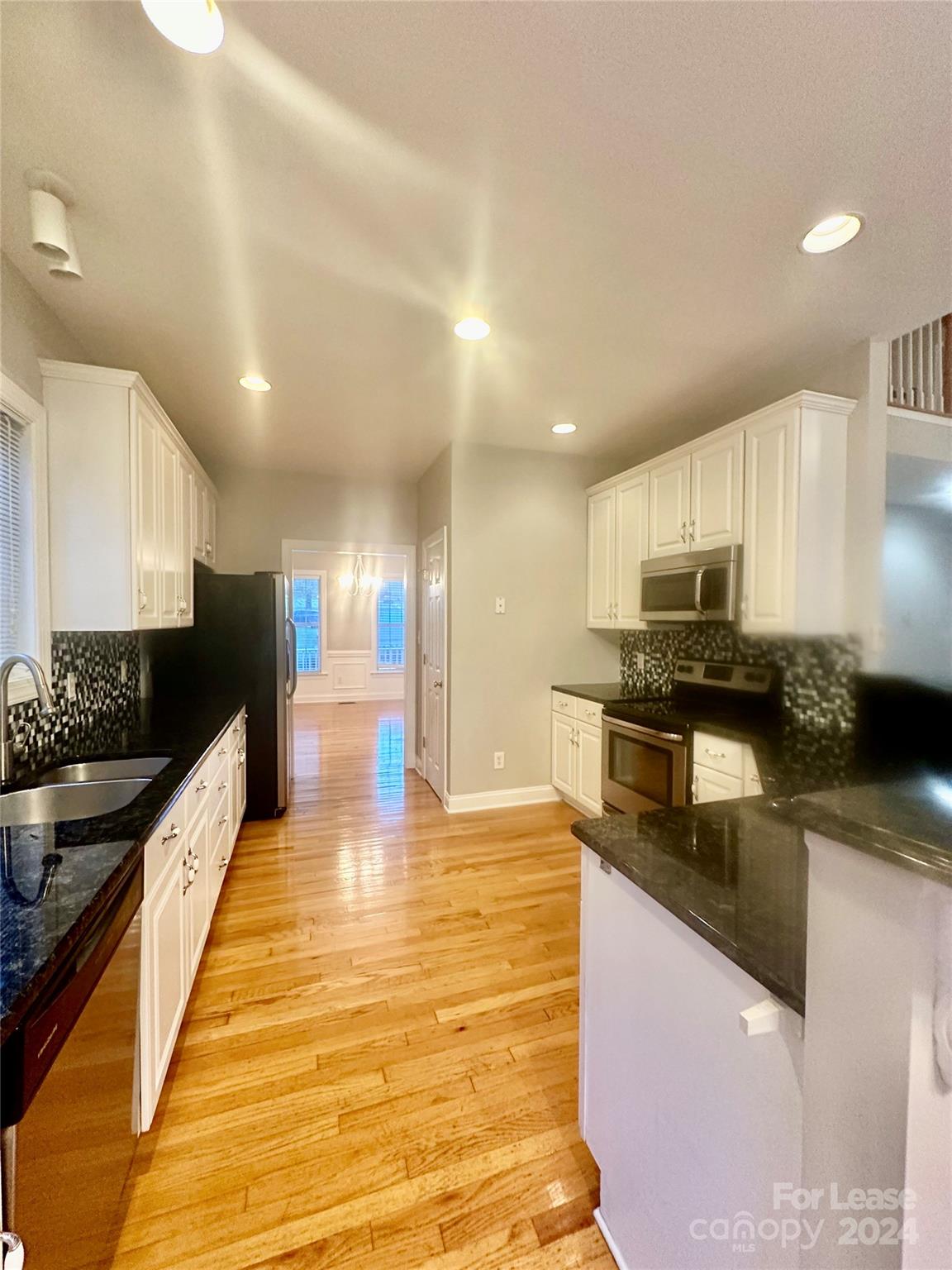 a large kitchen with granite countertop lots of counter top space and stainless steel appliances