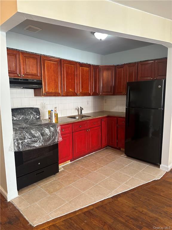 Kitchen with black appliances, tasteful backsplash, light wood-type flooring, and sink