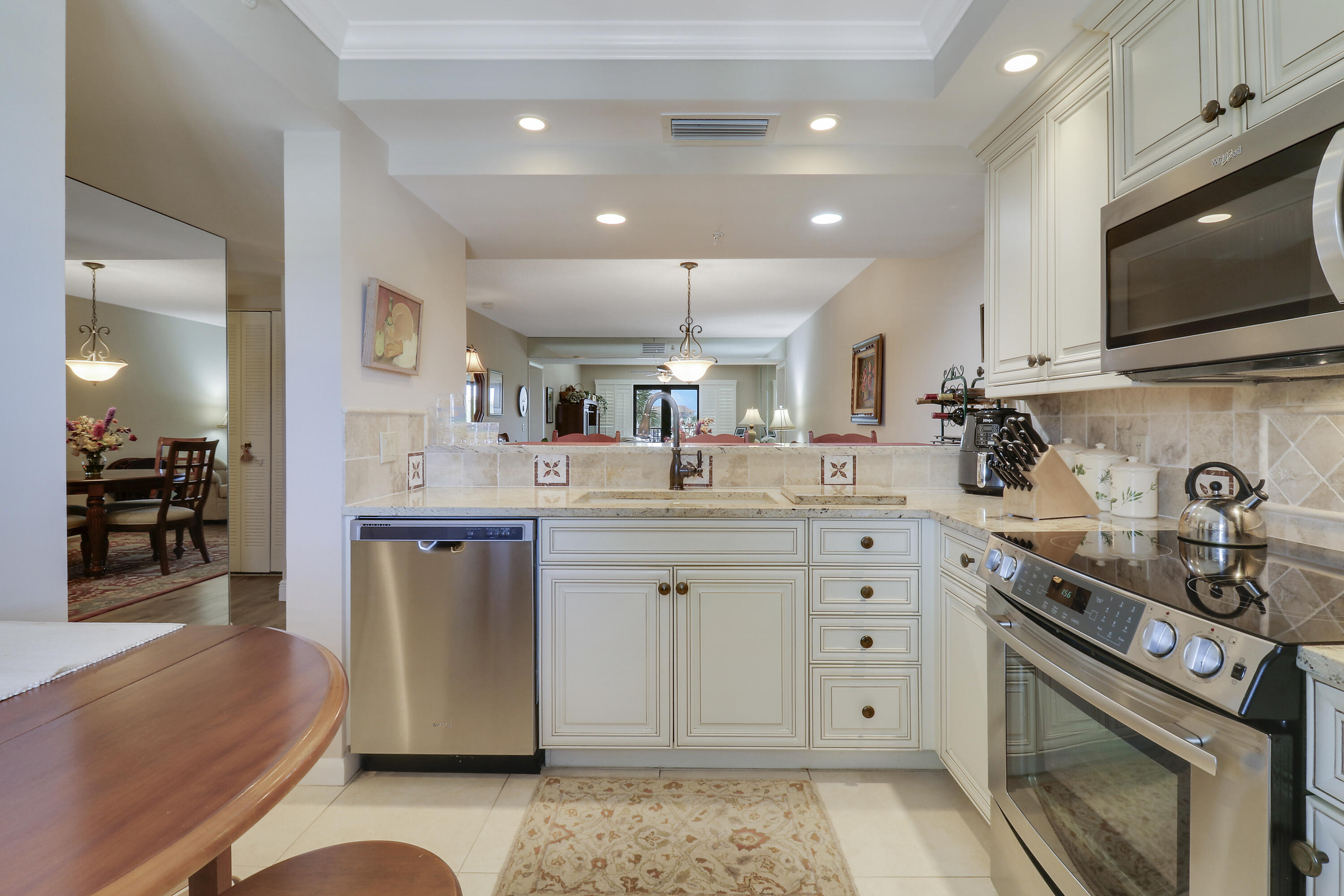 a kitchen with stainless steel appliances kitchen island granite countertop a sink dishwasher stove and white cabinets with wooden floor