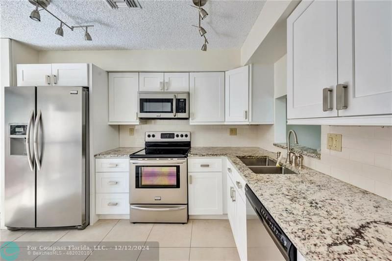 a kitchen with kitchen island granite countertop a sink stainless steel appliances and counter space