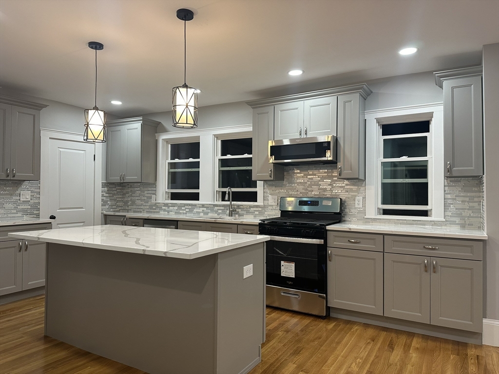 a kitchen with stainless steel appliances granite countertop a stove a sink and a wooden floors