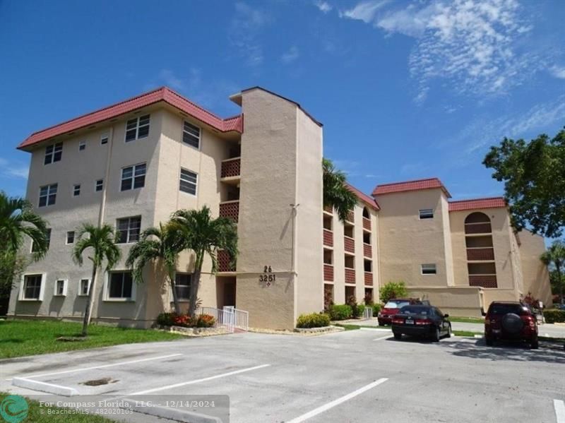 a front view of a building with cars parked