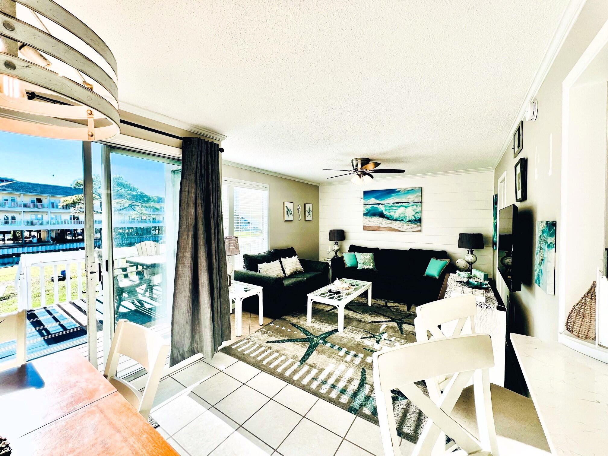 a living room with furniture a flat screen tv and a floor to ceiling window