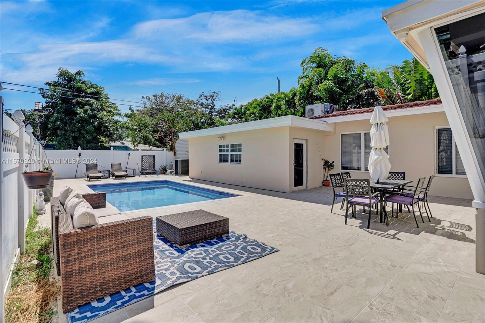 a view of a patio with couches table and chairs with potted plants and big yard