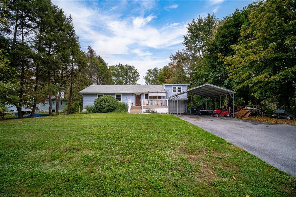 View of front of property with a front yard and a carport