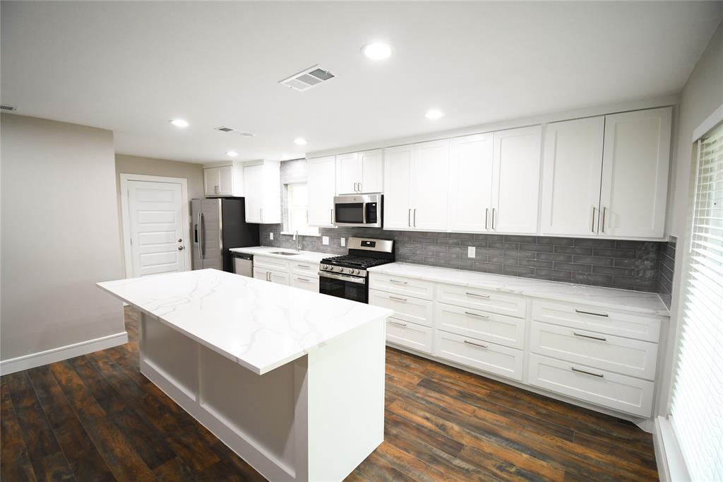 a kitchen with granite countertop white cabinets and stainless steel appliances