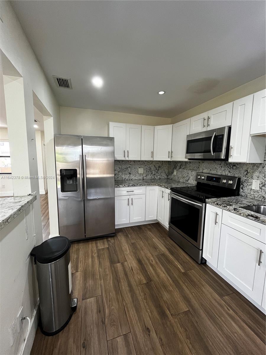 a kitchen with granite countertop a refrigerator stove top oven and sink