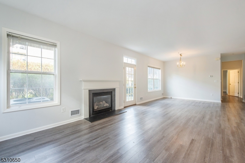 an empty room with wooden floor fireplace and windows