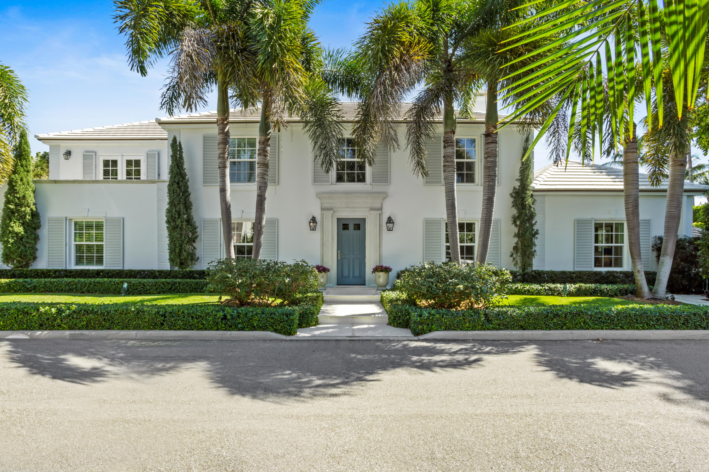 a view of a house in front of a yard with palm trees