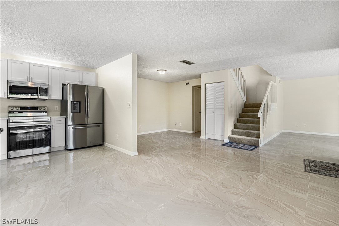 a view of kitchen with refrigerator and white cabinets