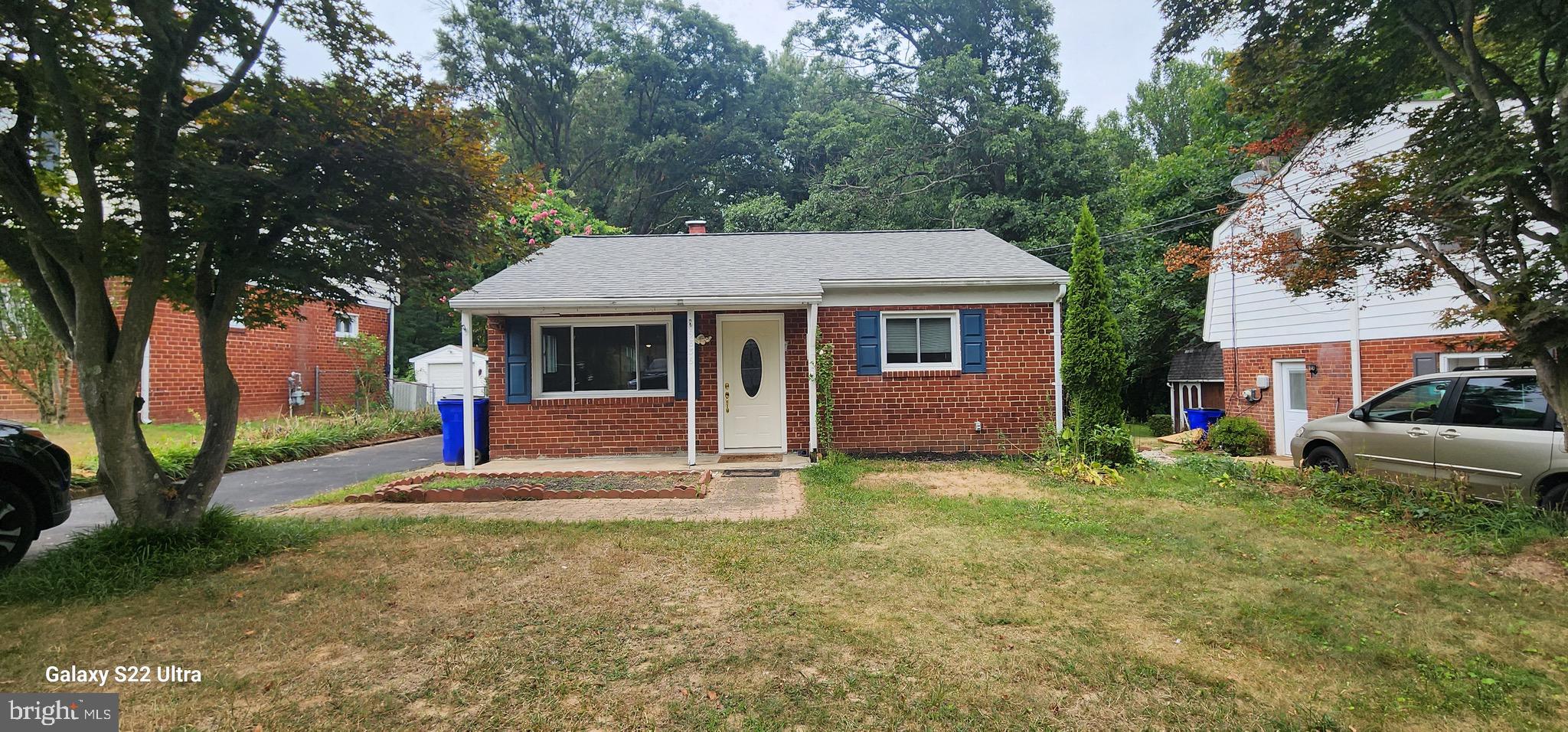 a view of a house with a yard and large tree