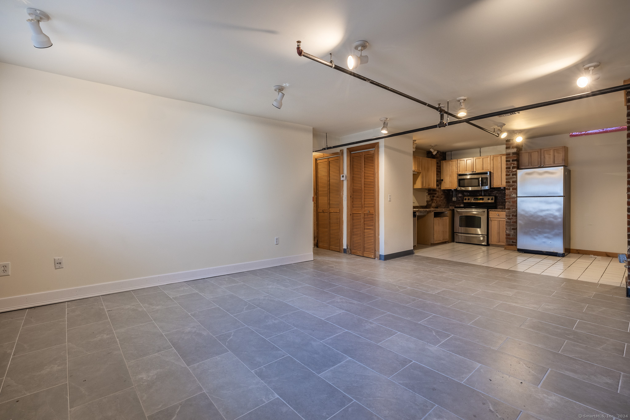 an empty room with closet and a kitchen