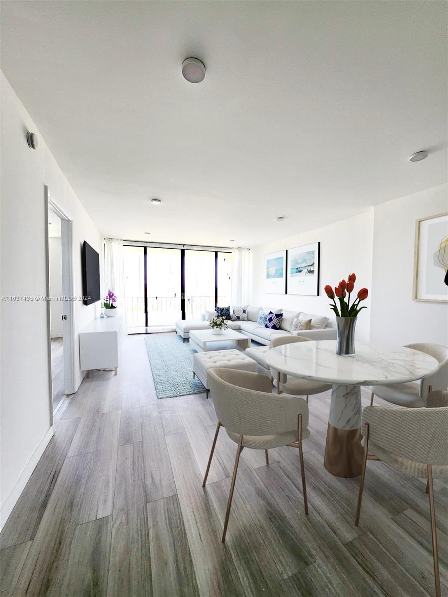 a living room with couches and kitchen view with wooden floor