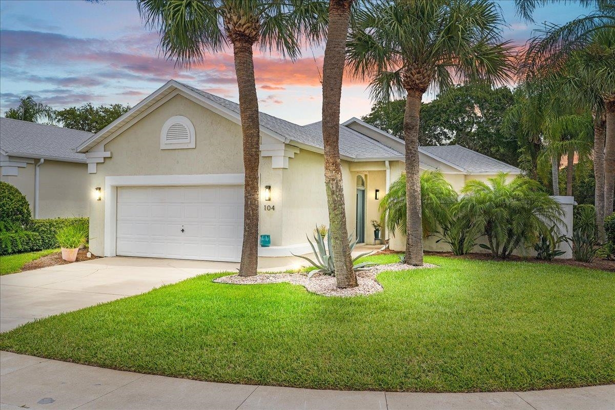 a front view of a house with a yard and palm trees