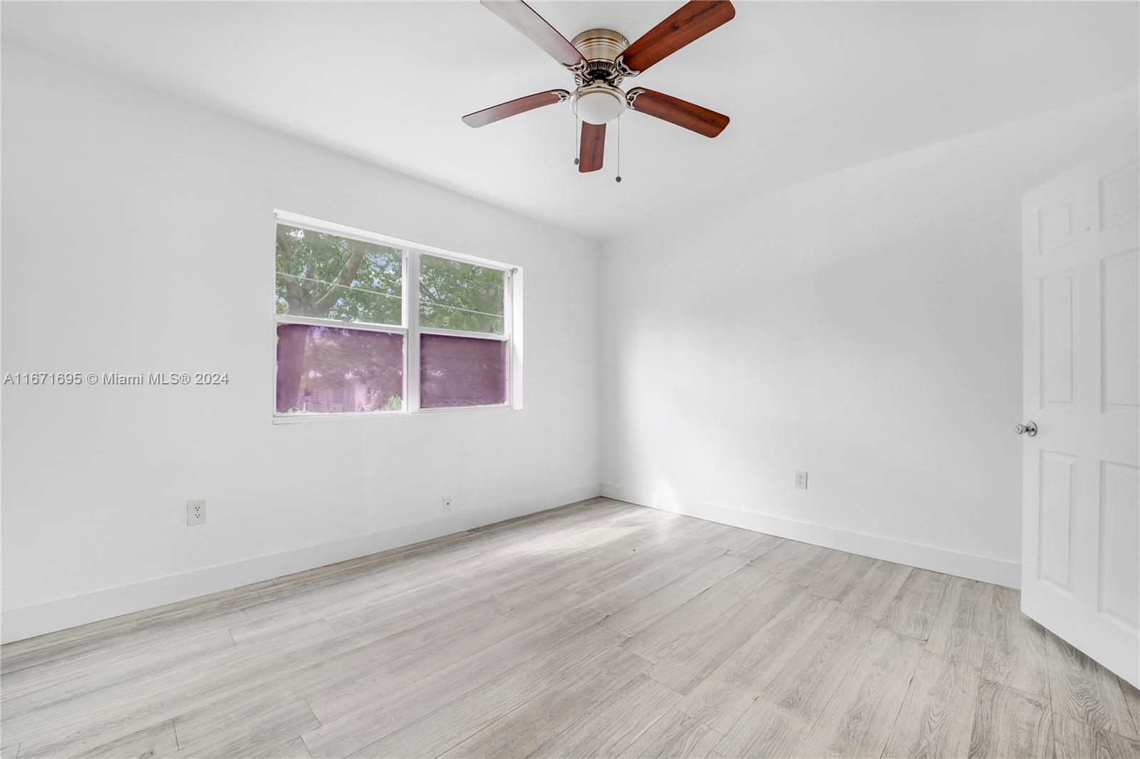 an empty room with wooden floor fan and windows