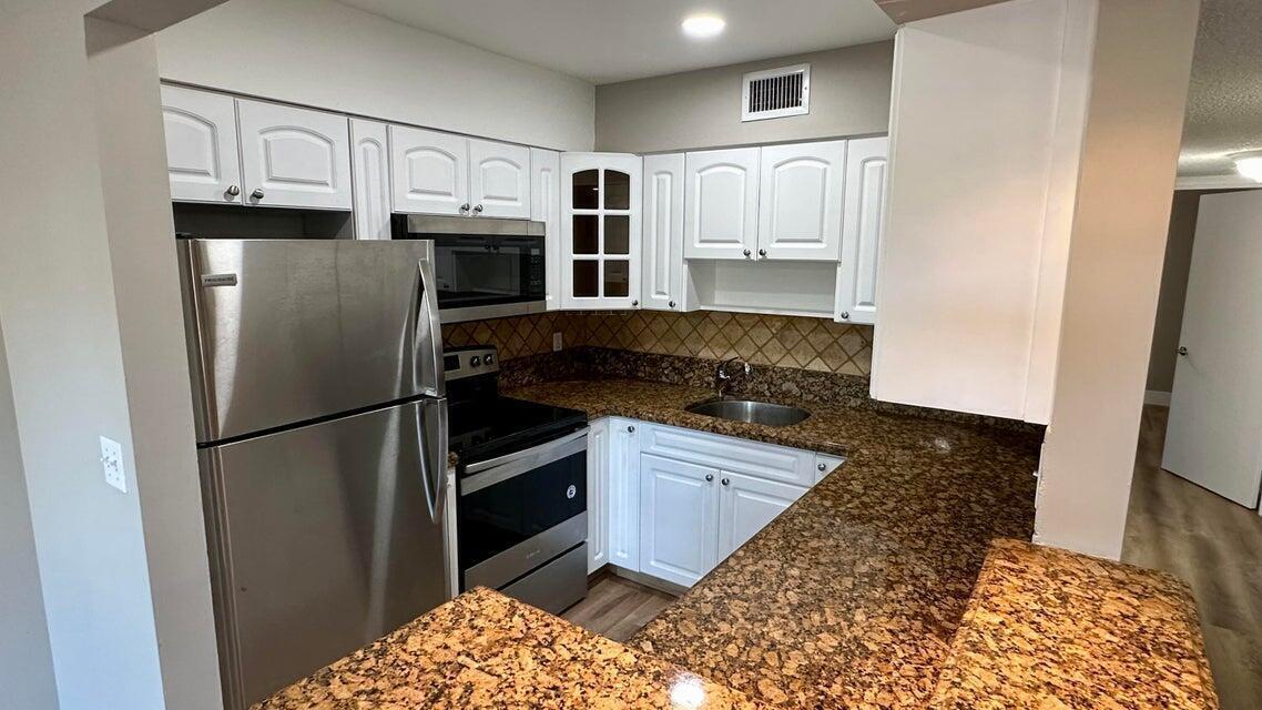 a kitchen with granite countertop a refrigerator and a stove top oven