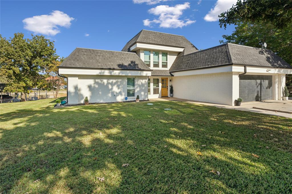 a view of a house with a big yard and large tree