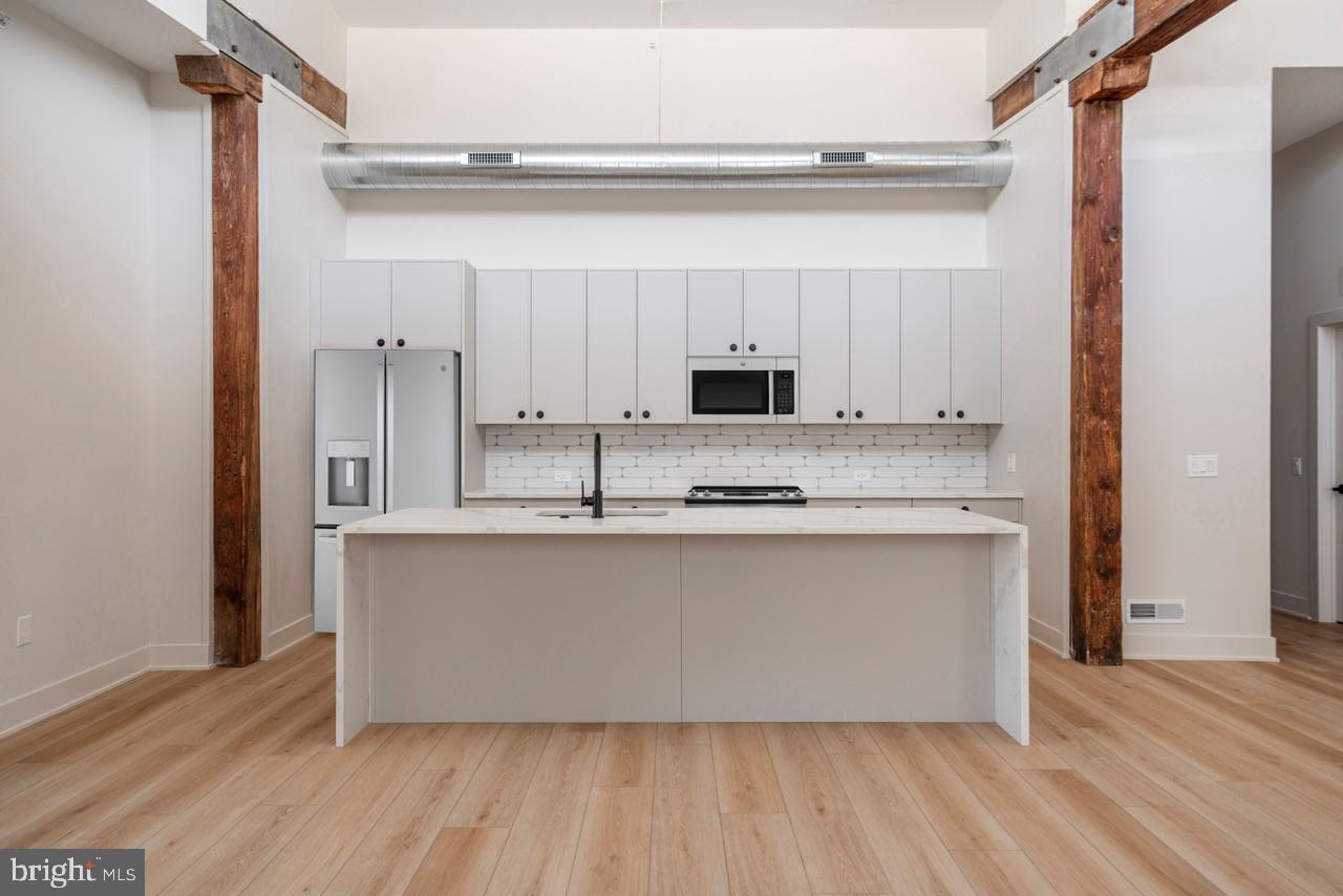 a room with kitchen island stainless steel appliances a sink and refrigerator