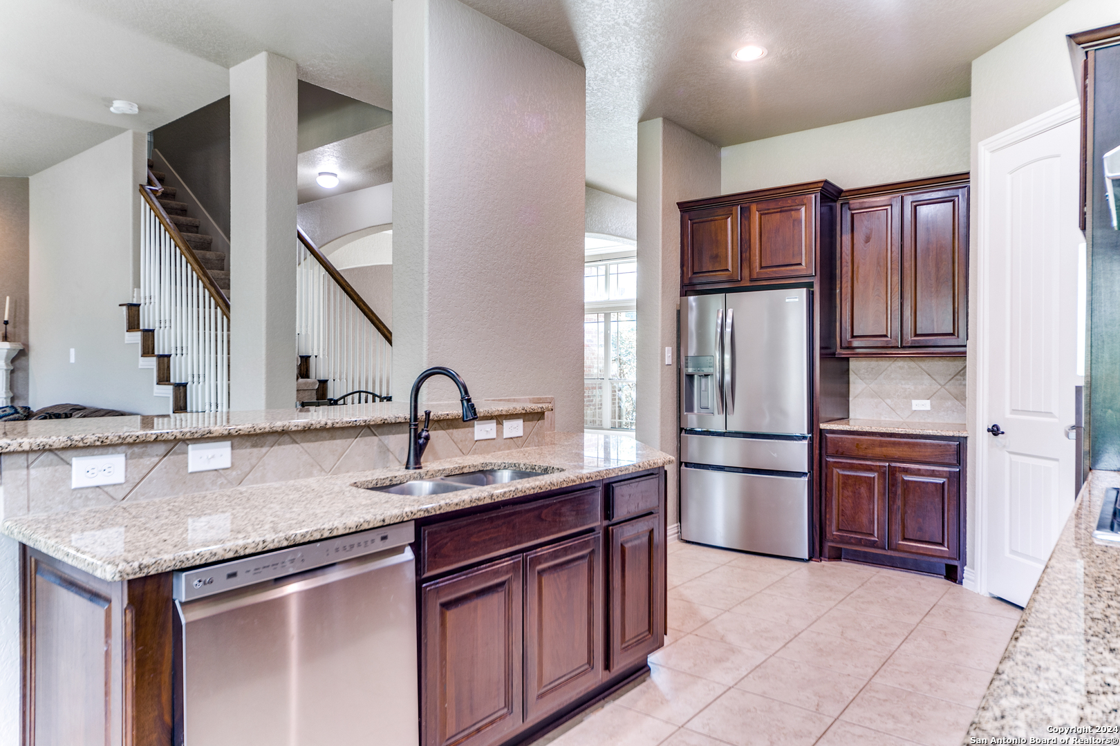 a kitchen with stainless steel appliances granite countertop a sink refrigerator and cabinets