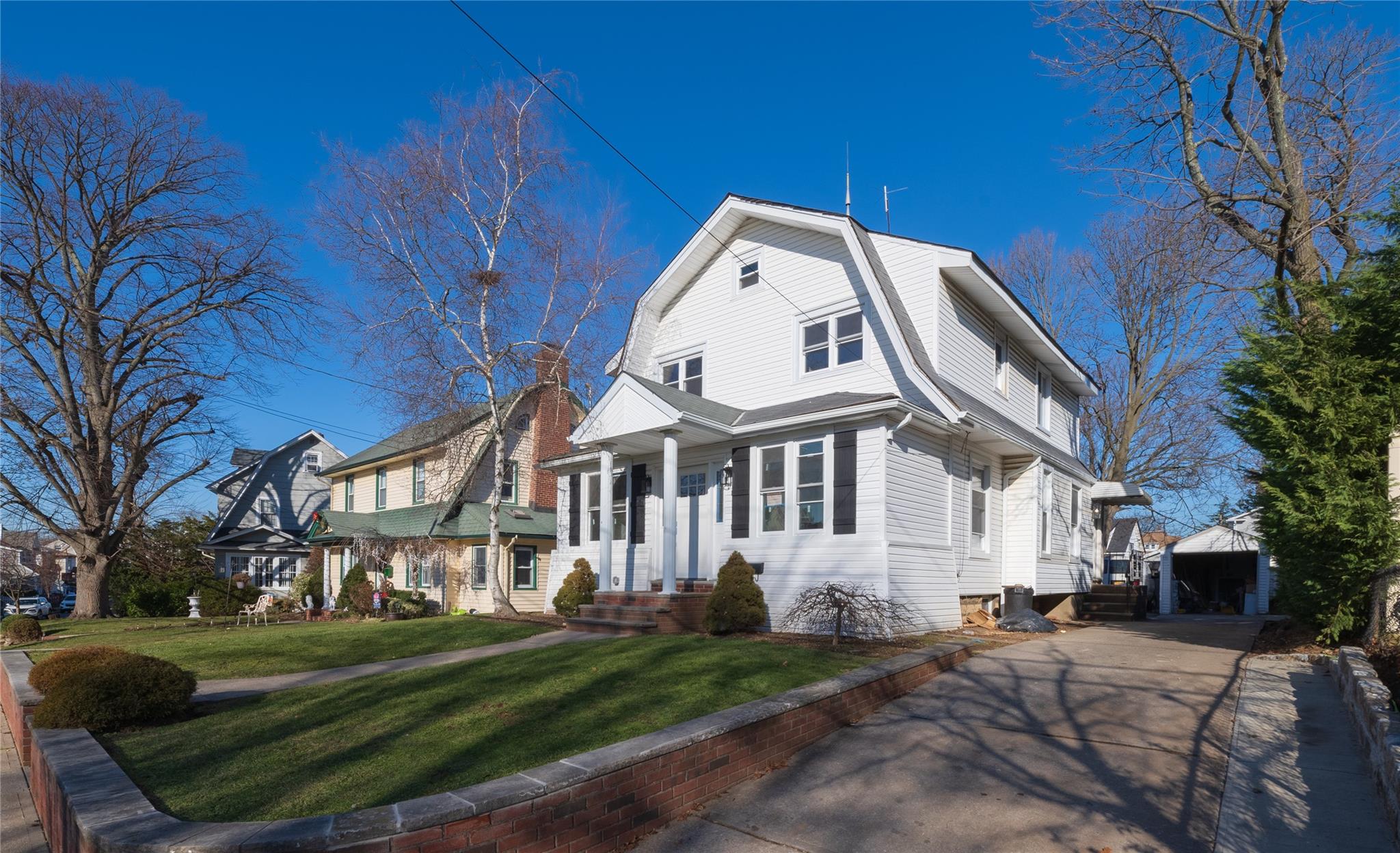 View of front of house with a garage, an outbuilding, a front yard, and central AC