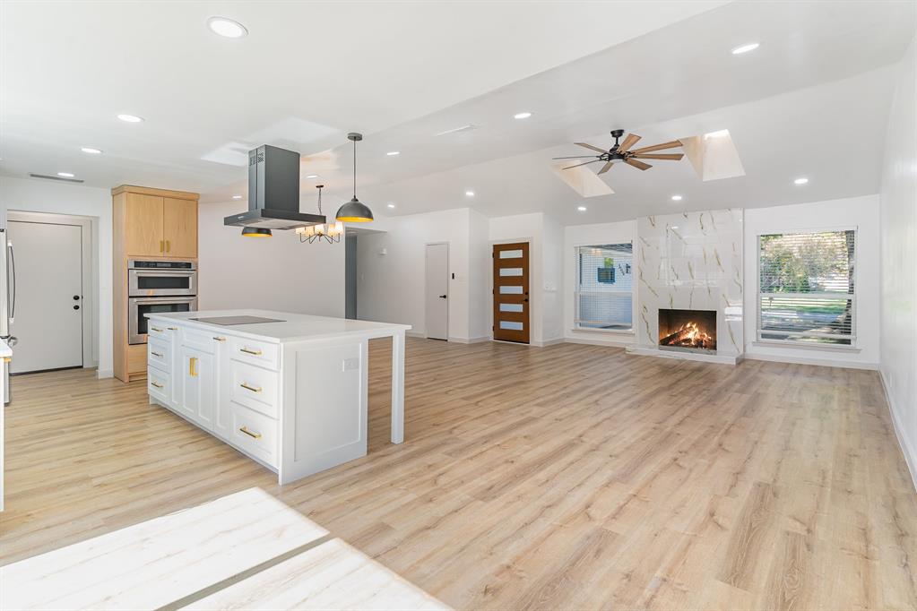 an empty room with wooden floor fireplace and windows