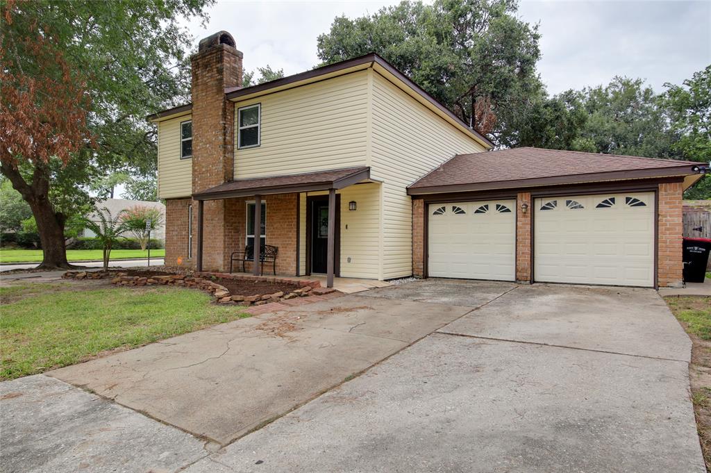 a view of a house with a yard plants and large tree