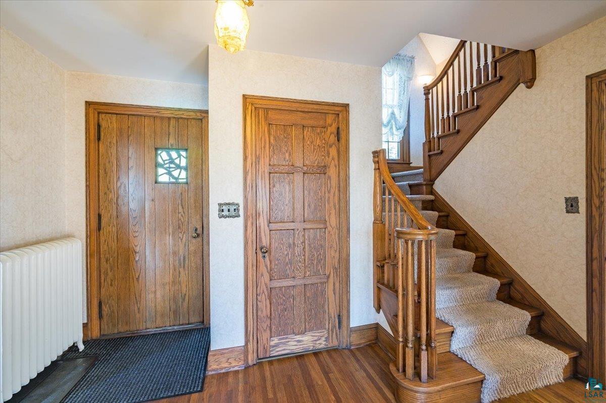 Foyer entrance featuring dark wood-type flooring and radiator