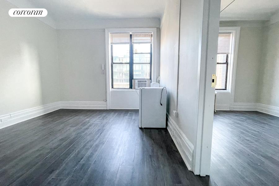 an empty room with wooden floor and windows