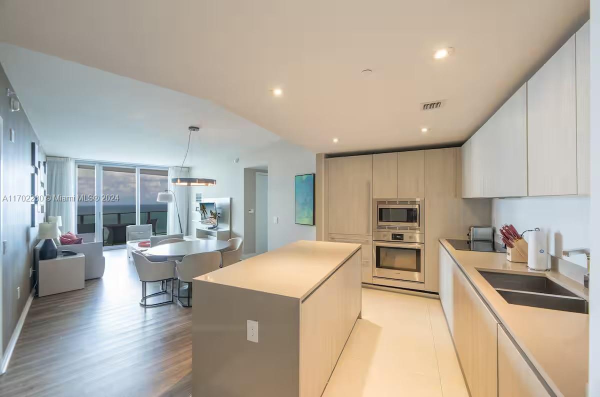 a kitchen with a dining table chairs stove and white cabinets