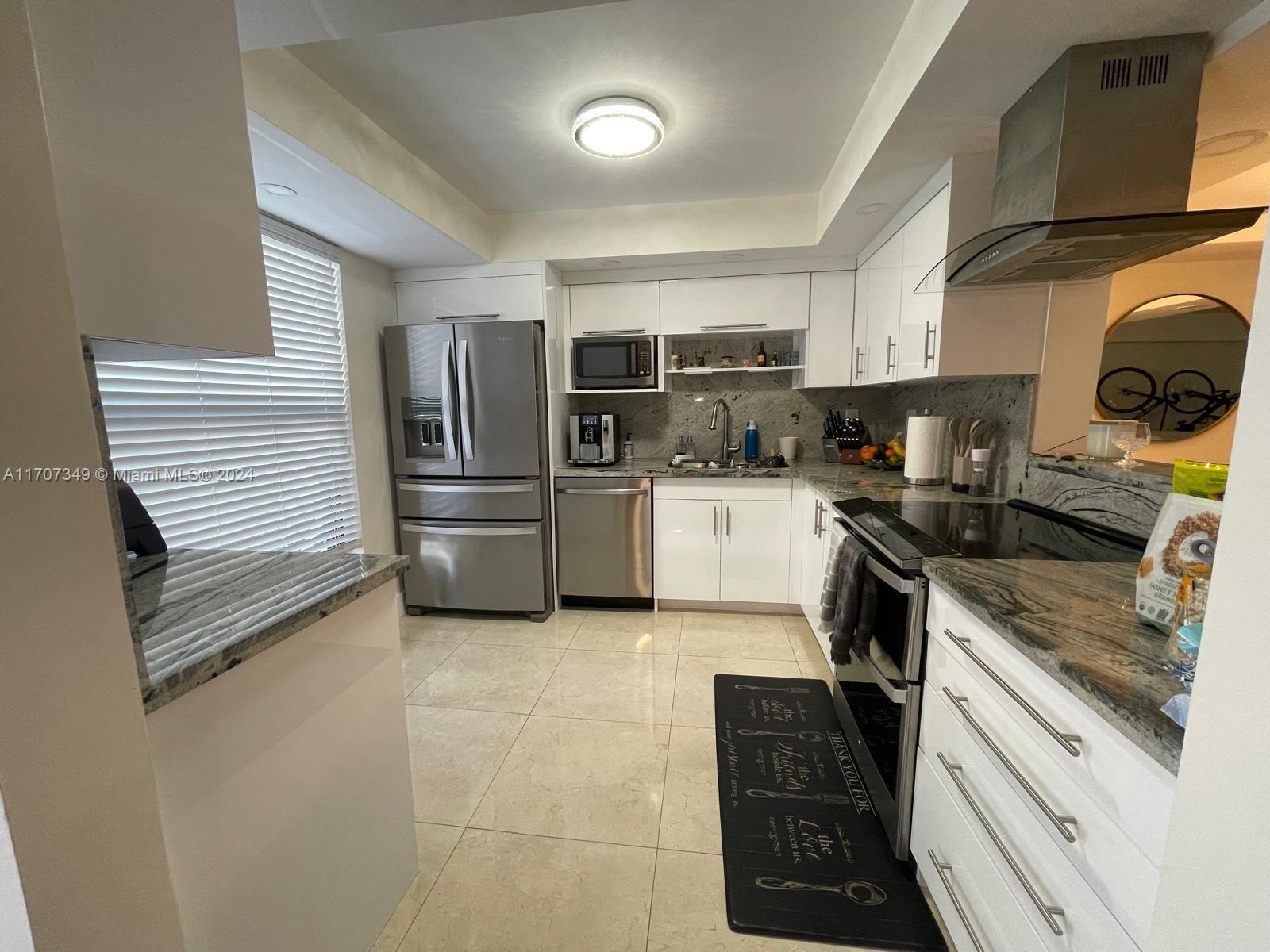 a kitchen with granite countertop a refrigerator and a stove top oven