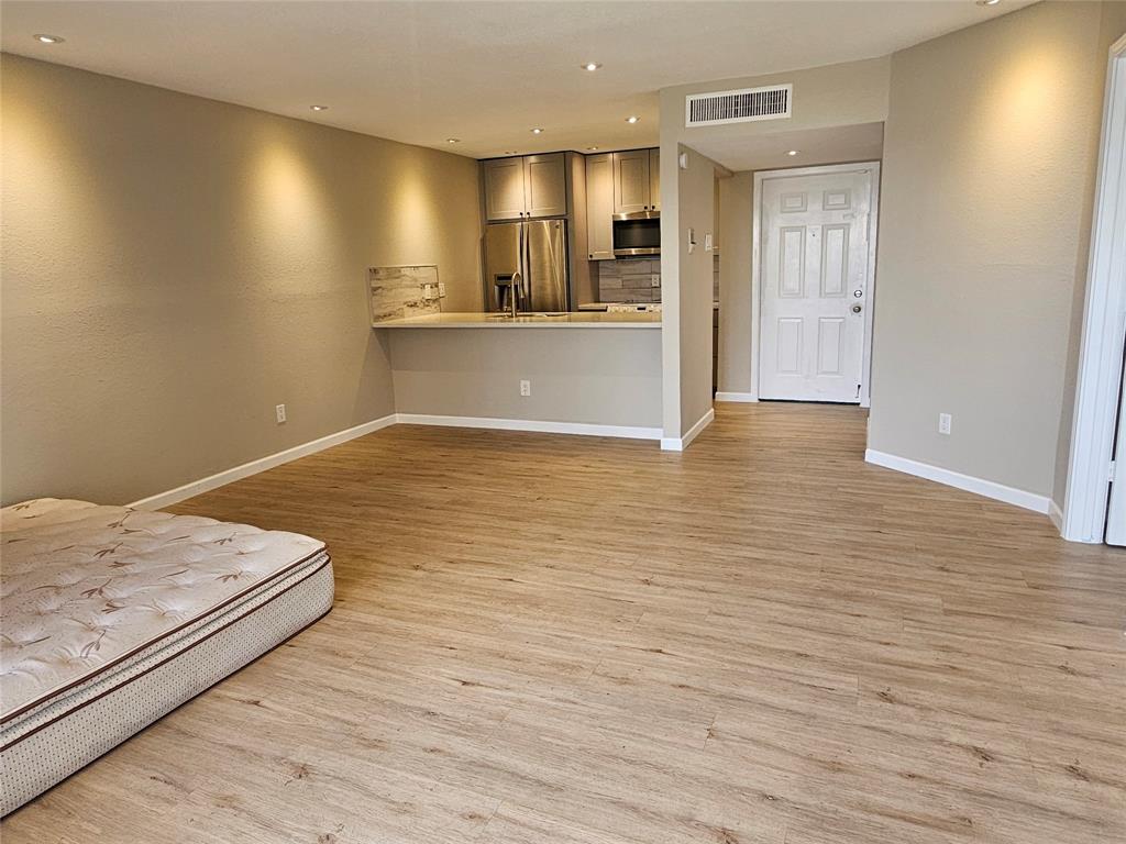 a view of a kitchen with wooden floor and a refrigerator