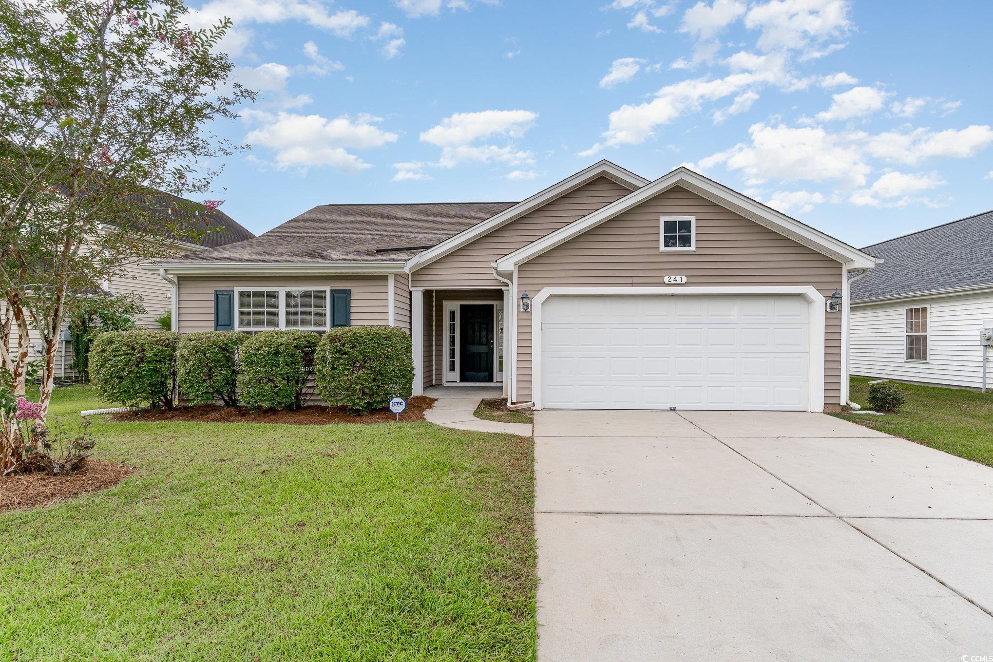 Single story home featuring a front yard and a gar