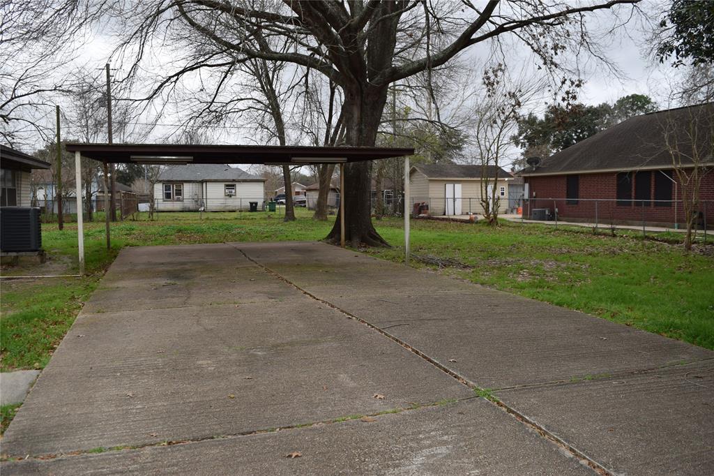 a view of house with a big yard and large trees