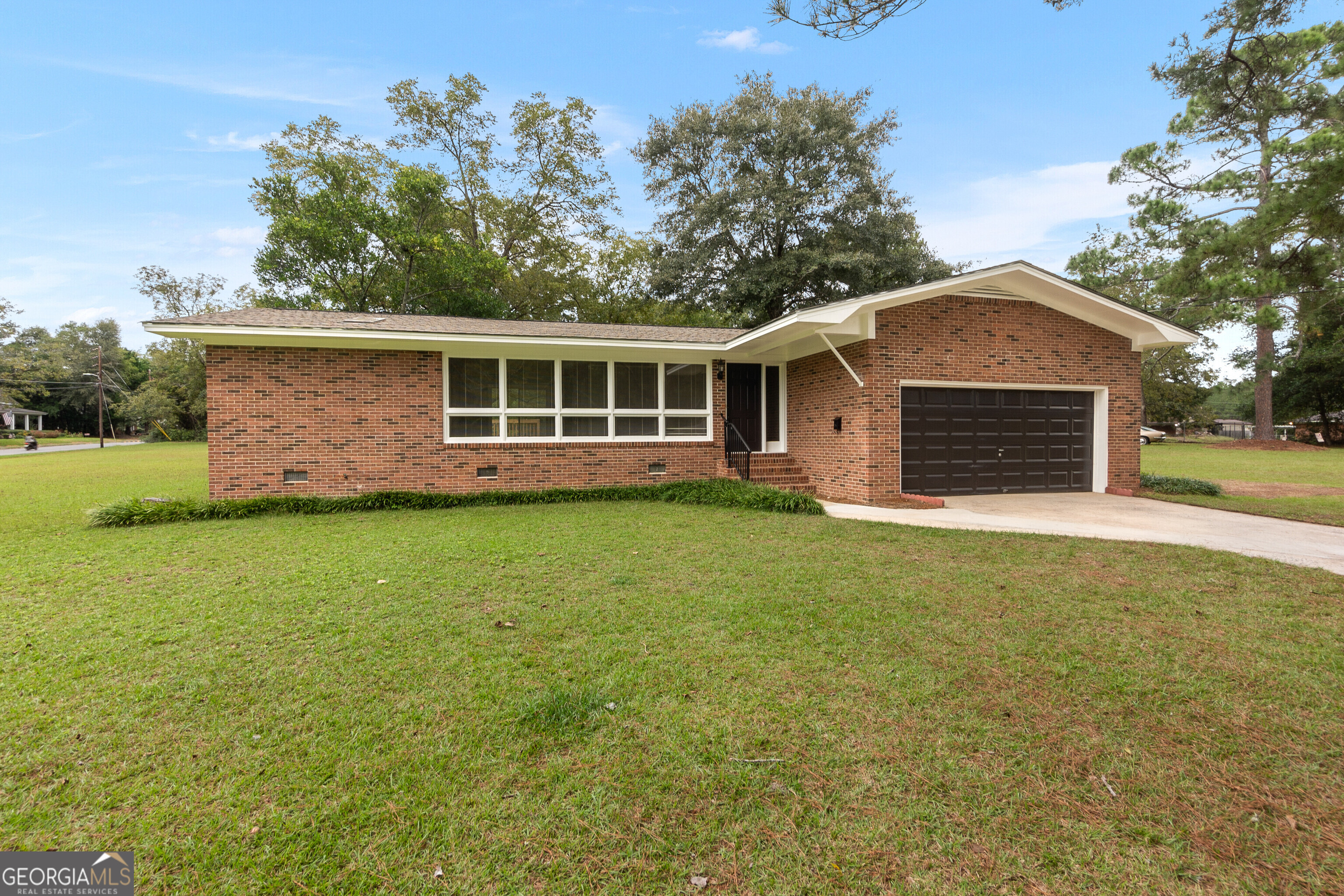 a front view of house with yard and trees in the background