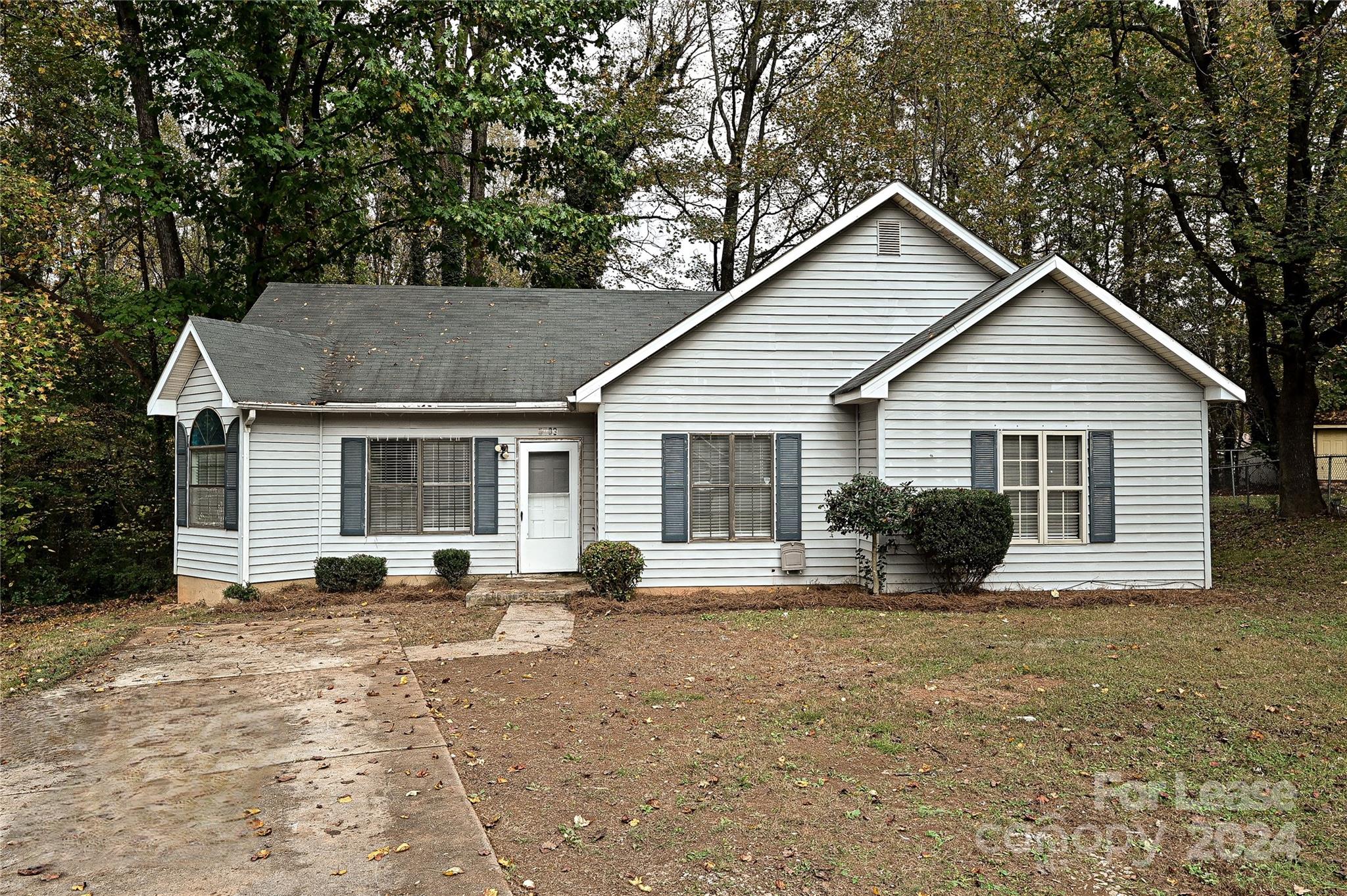 a view of a house with a yard and large trees