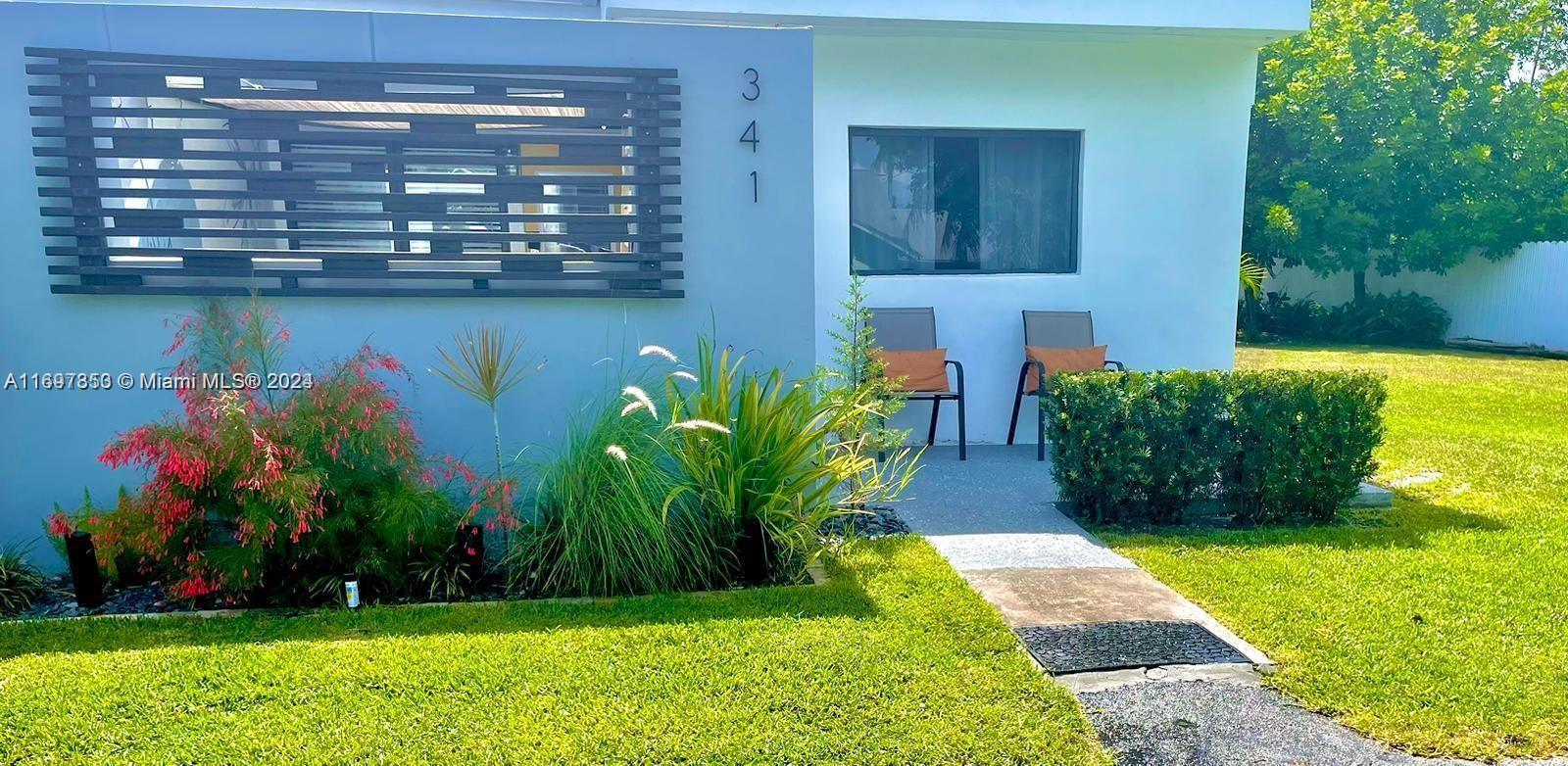 a view of front door of house and yard with green space