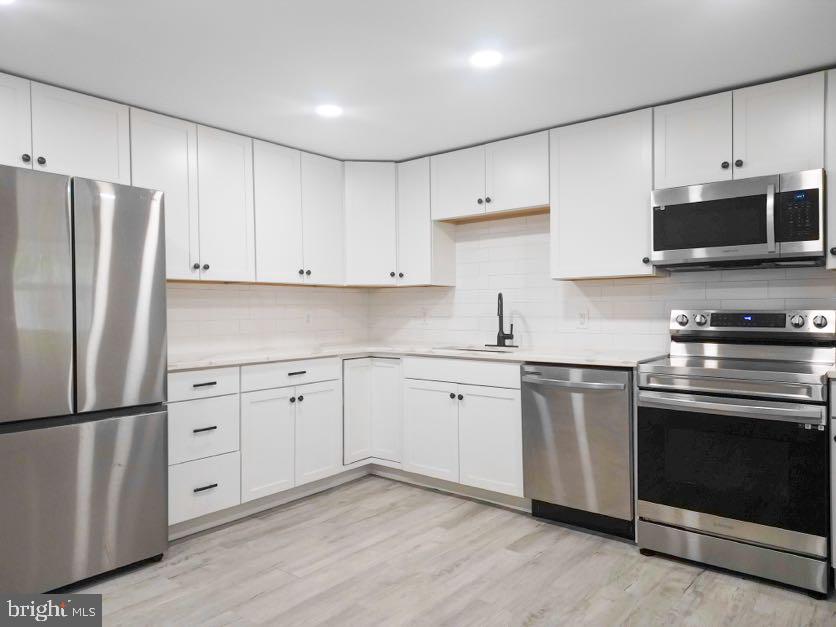 a kitchen with white cabinets white stainless steel appliances and sink