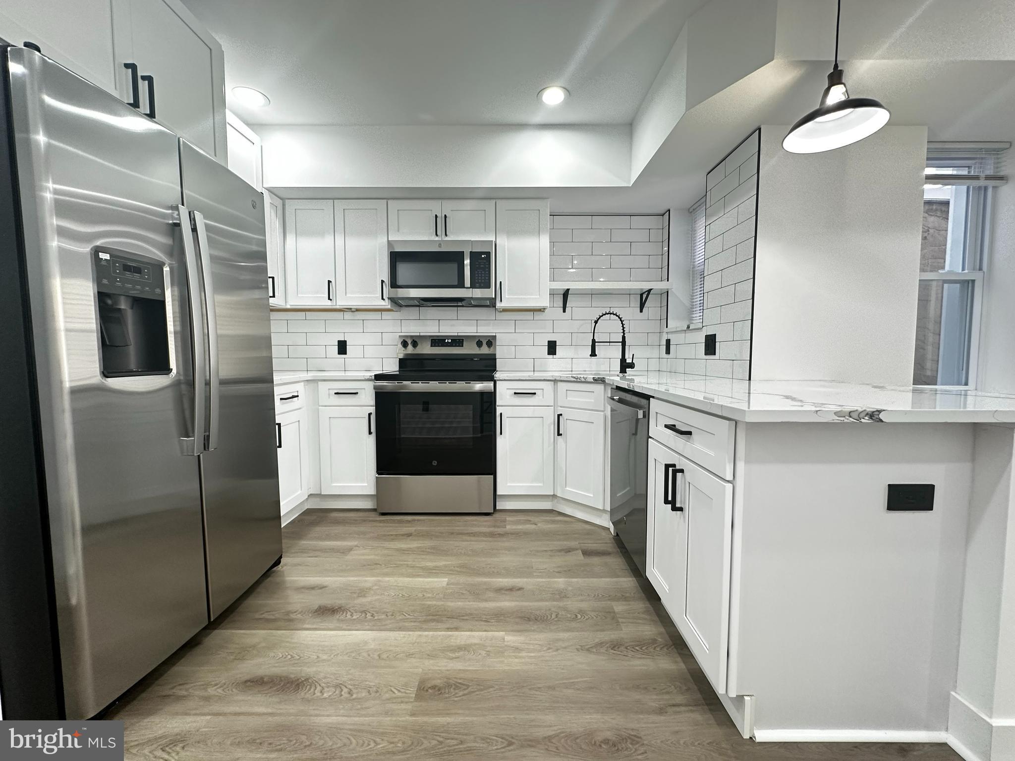 a kitchen with stainless steel appliances granite countertop a refrigerator a stove top oven a sink and dishwasher