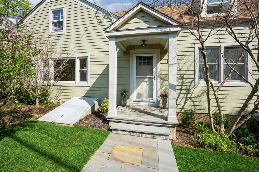 a view of a white house with a small yard and plants