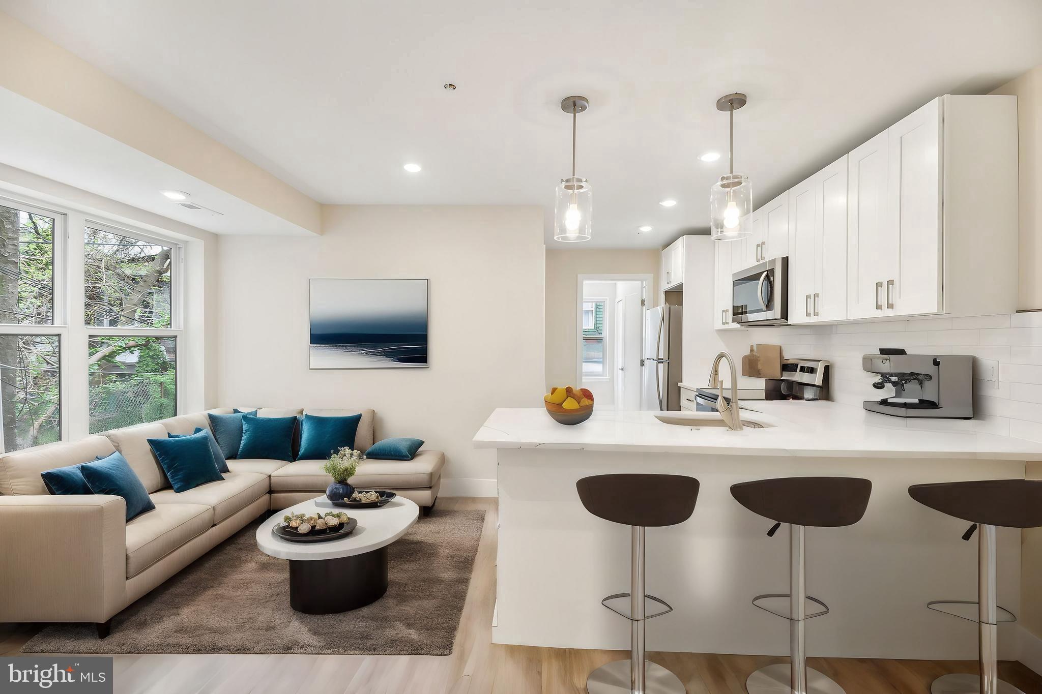 a living room with furniture kitchen view and a wooden floor