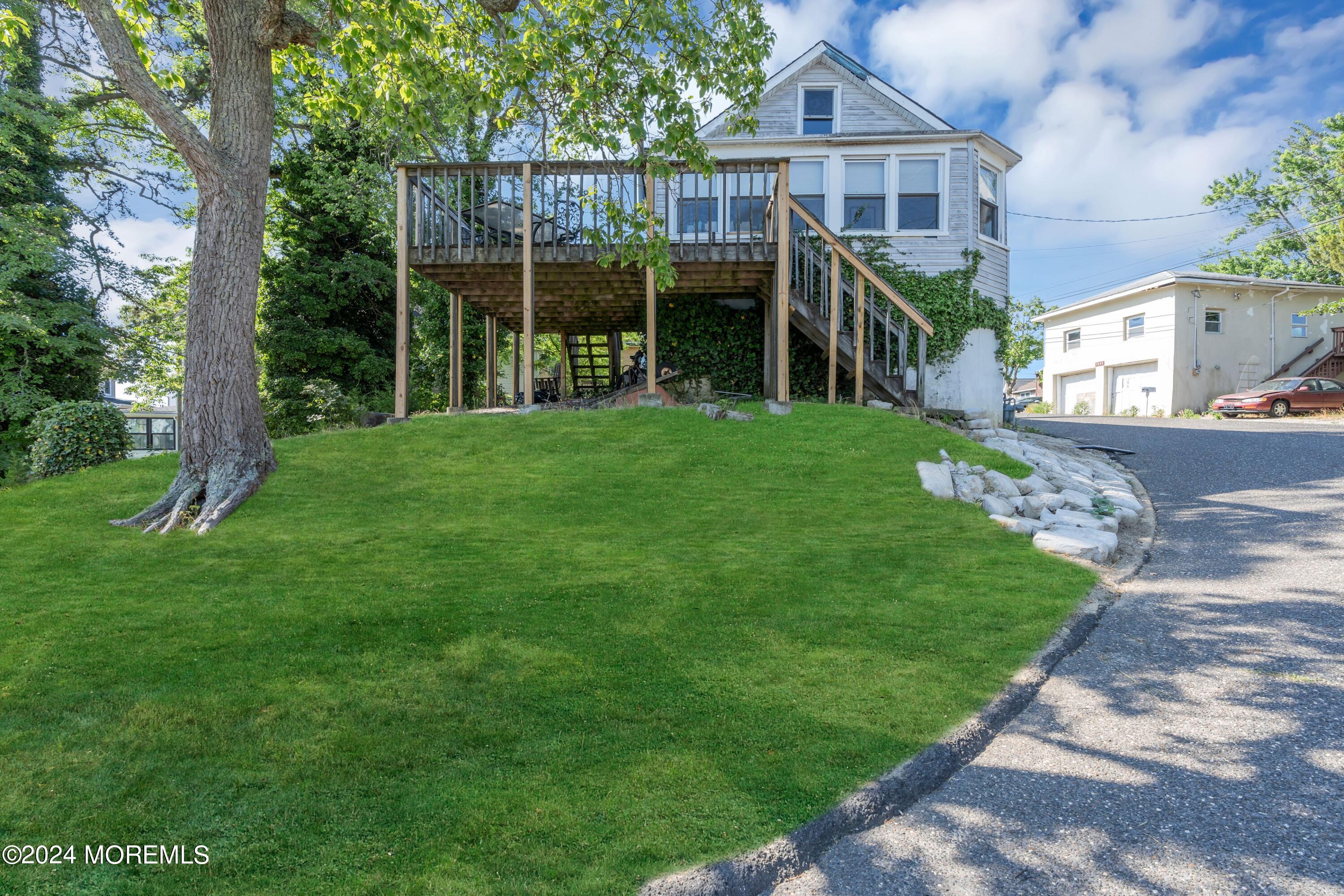 a view of a house next to a big yard and large trees